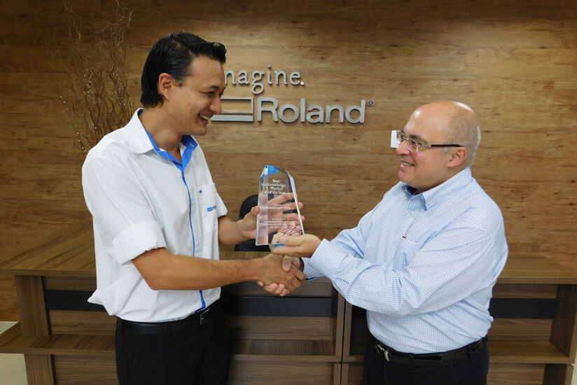 Roland DG Brasil President Celso Roberto Bento (right) presenting a trophy to Marcelo  Gomes Botao (left)
