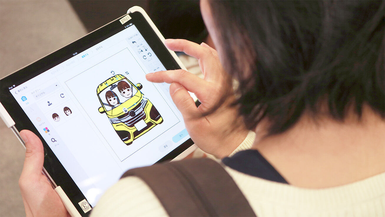 タブレット端末で似顔絵や顔写真をクルマのイラスト上にレイアウトして、キーホルダーのデザインを作ります