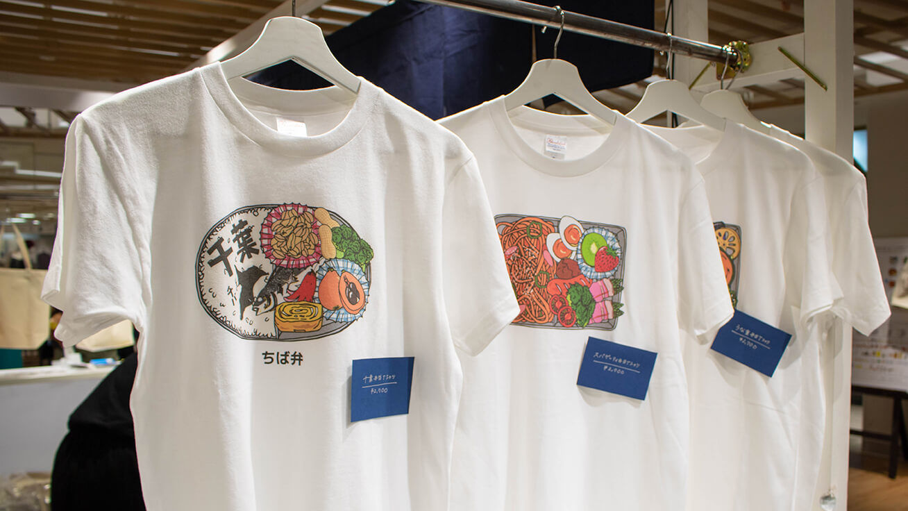 イベント限定デザイン、落花生などの千葉名物が詰まった「ちば弁」Tシャツ(左)