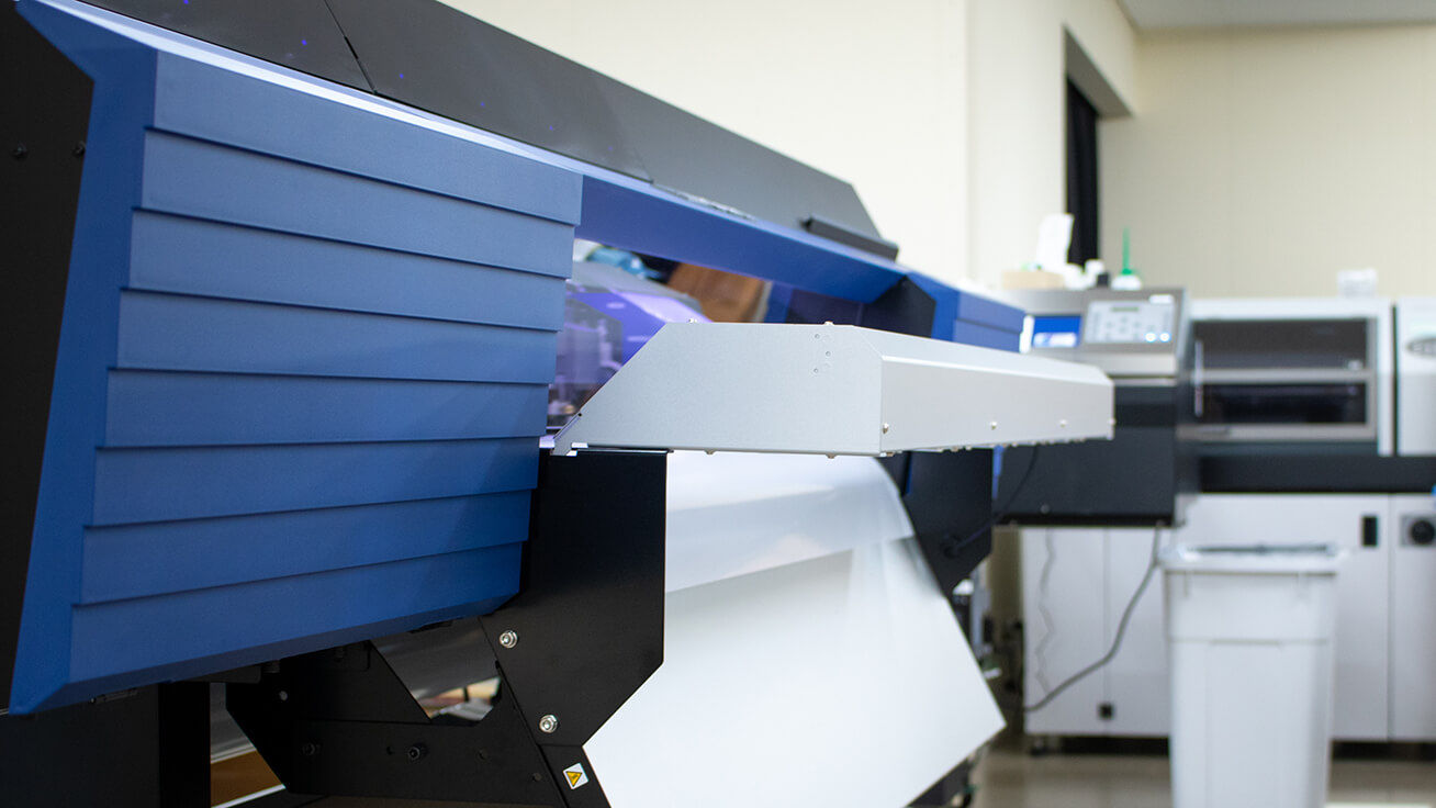 Roland DG’s TrueVIS VG2-540 wide-format printer/cutter (foreground) and VersaUV LEF2-200 UV printer (background)