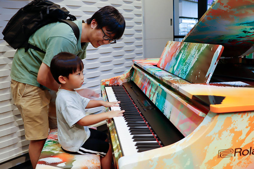 Parent and child playing the art-wrapped piano