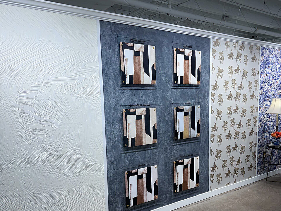 View of wall with samples of wall coverings, including white, textured output from DG DIMENSE.